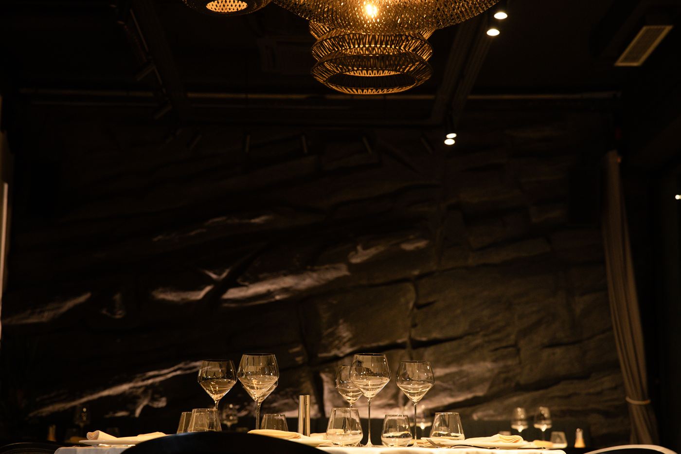 Enterijer restorana — kameni zid i poređane čaše za vino