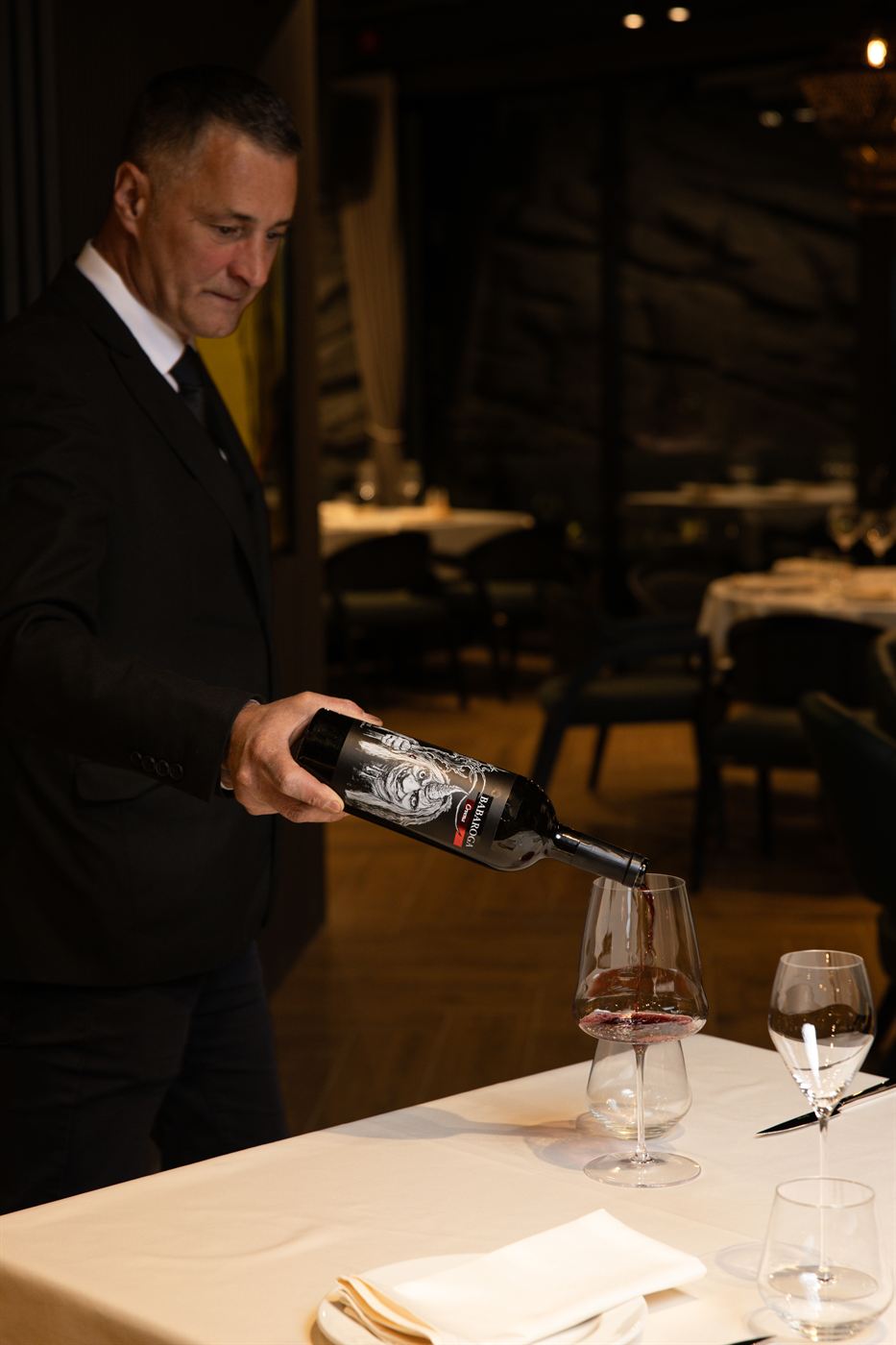 Konobar služi vino za stolom u restoranu