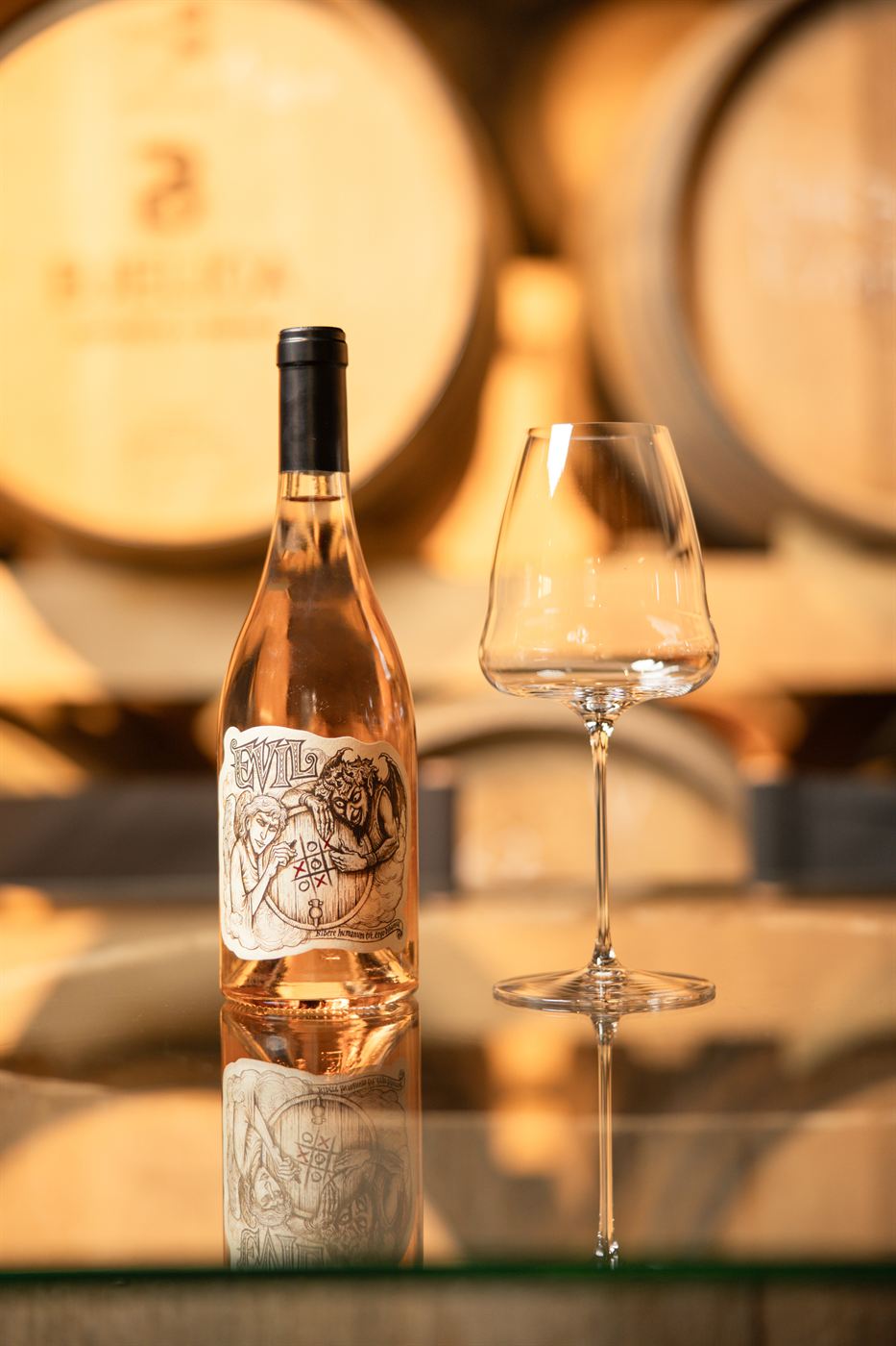 Boca roze vina Evil sa čašom u podrumu vinarije